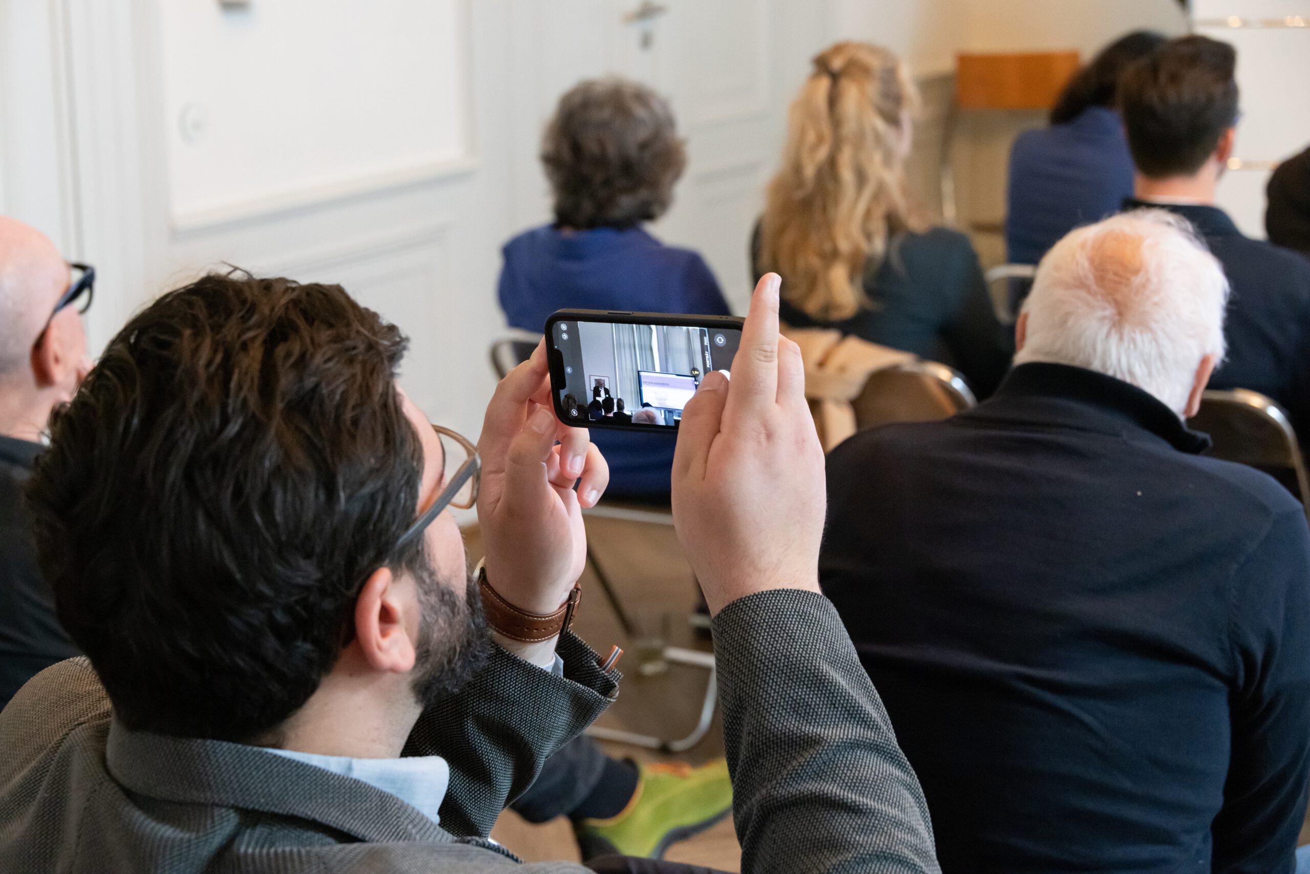 Ein Teilnehmer hält die Eröffnungsrede auf dem Smartphone fest