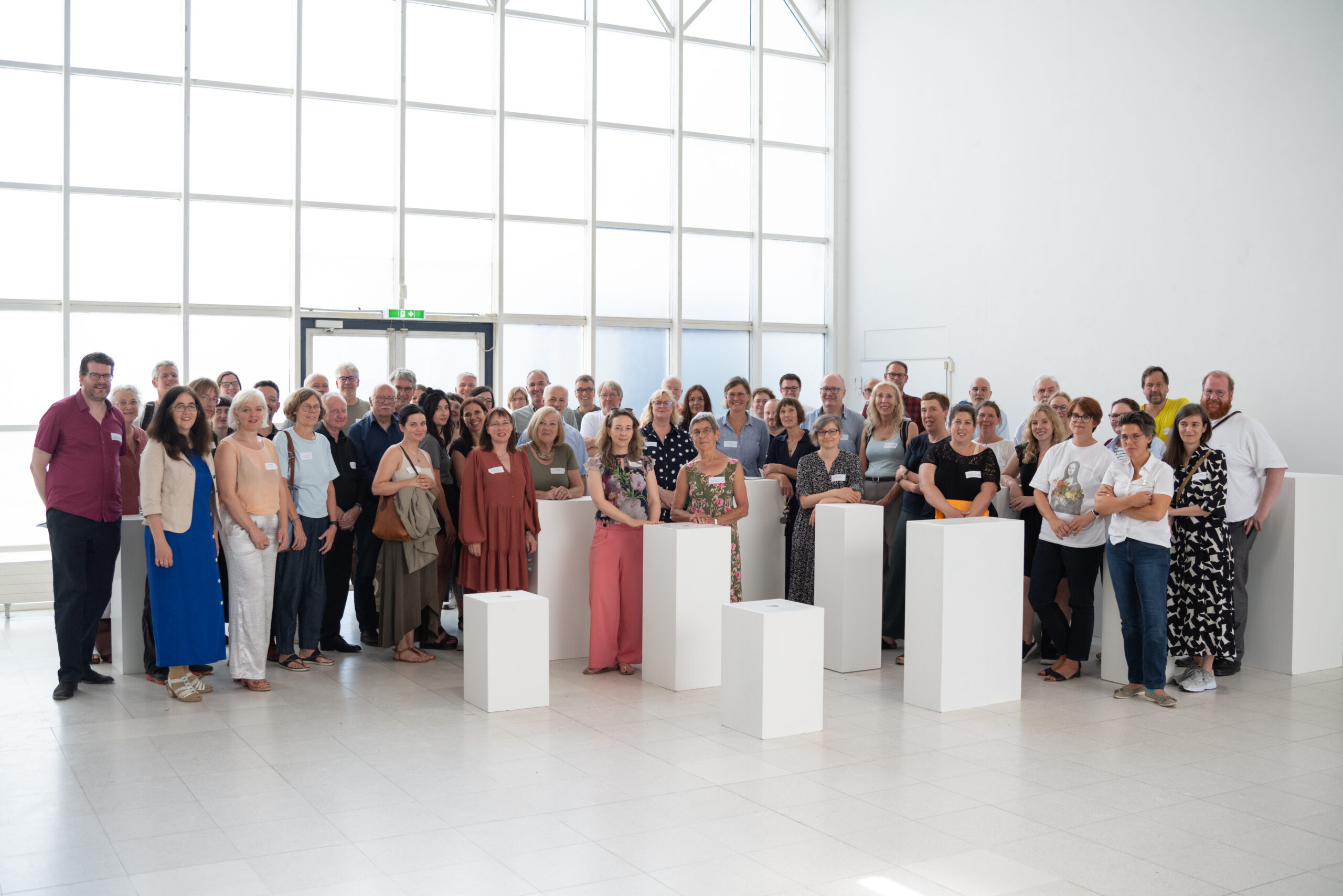 Gruppenbild mit allen Teilnehmenden des letzten Themenforums der Kulturentwicklungsplanung in RLP. Die Teilnehmenden stehen in einer großen Halle. Vor ihnen sind ein paar Podeste gestellt, die unterschiedlich hoch sind.